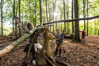 Kinderen sjouwen takken en bouwen hutten in Boswachterij Westerschouwen in Burgh-Haamstede